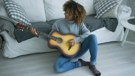Mujer-Joven-Tocando-La-Guitarra-En-Casa