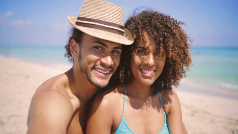 Couple-looking-at-camera-on-beach