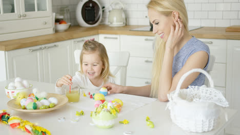 Laughing-woman-and-little-girl-coloring-eggs