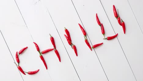A-word-CHILLI-formed-with-small-red-chilli-peppers--Placed-on-white-wooden-table