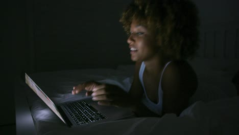 Smiling-woman-chatting-with-laptop-in-dark