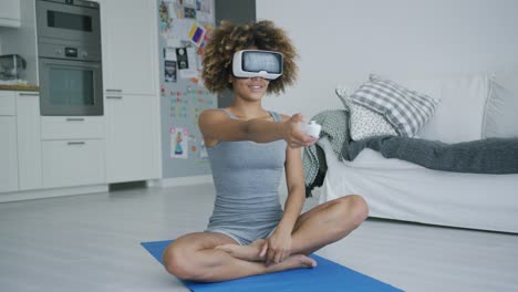 Cheerful-sportswoman-in-VR-glasses-at-home