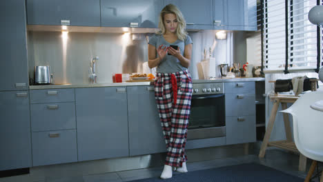 Young-woman-browsing-smartphone-in-kitchen