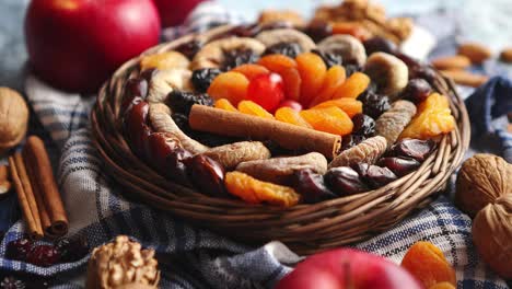 Composition-of-dried-fruits-and-nuts-in-small-wicker-bowl-placed-on-stone-table
