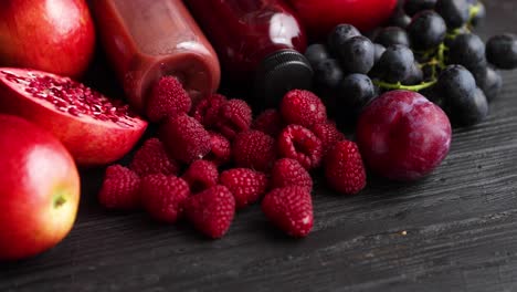 Various-fresh-red--purple-black-fruits--Mix-of-fruits-and-bottled-juices-on-black