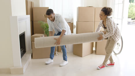Young-couple-carrying-a-rolled-rug-into-a-house