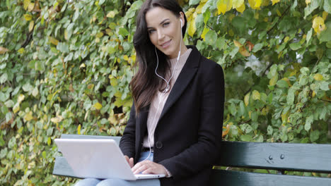 Smiling-woman-using-laptop-in-park