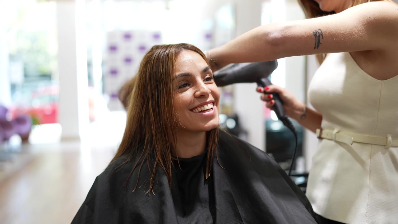 Parrucchiere professionista che asciuga i capelli del cliente in un salone
