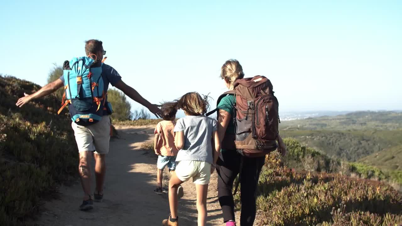padres y niños con mochilas caminando por el camino en las montañas