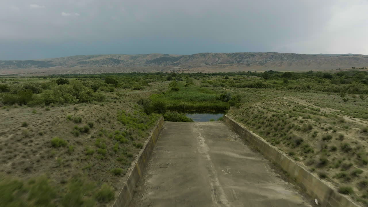 esclusa de presa de hormigón seco que conduce a un pequeño estanque pantanoso, georgia