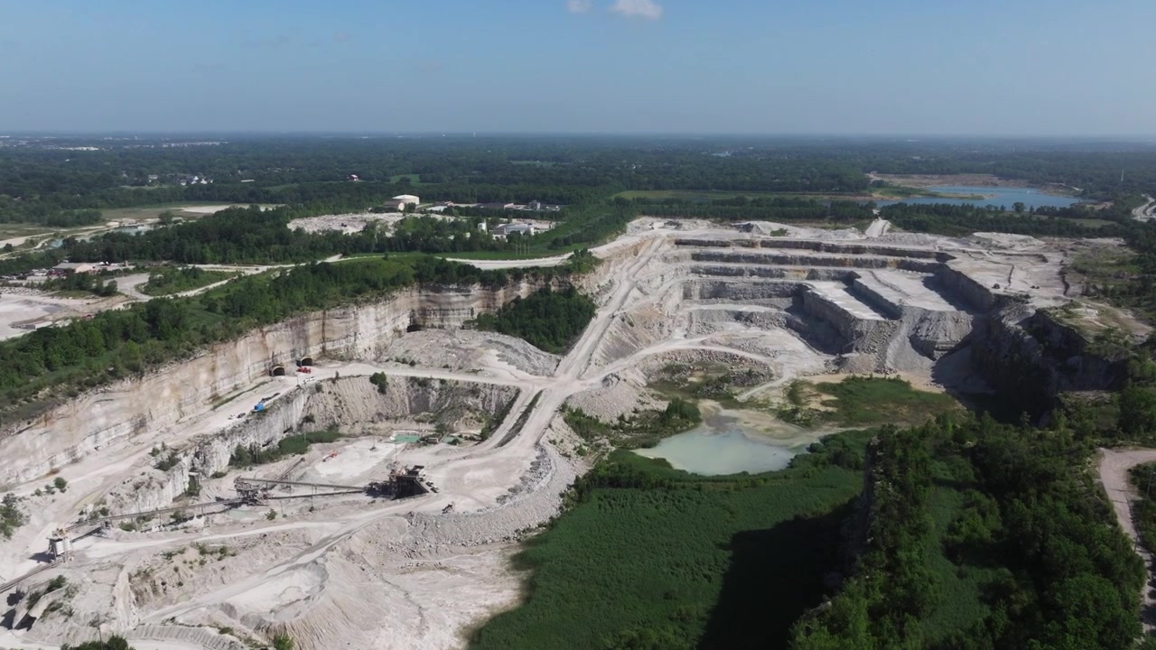 Forward Drone Shot Above the Terraced Walls and Tunnel Entrances of a Limestone Quarry