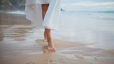 slim legs walk sand shore closeup. romantic girl stepping ocean shore in dress