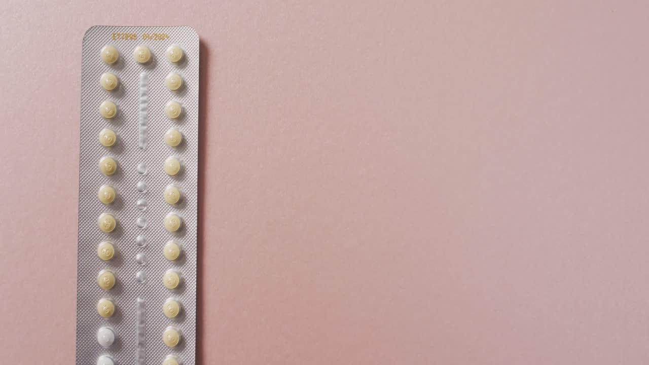Video en primer plano de pastillas amarillas sobre un fondo rosa.
