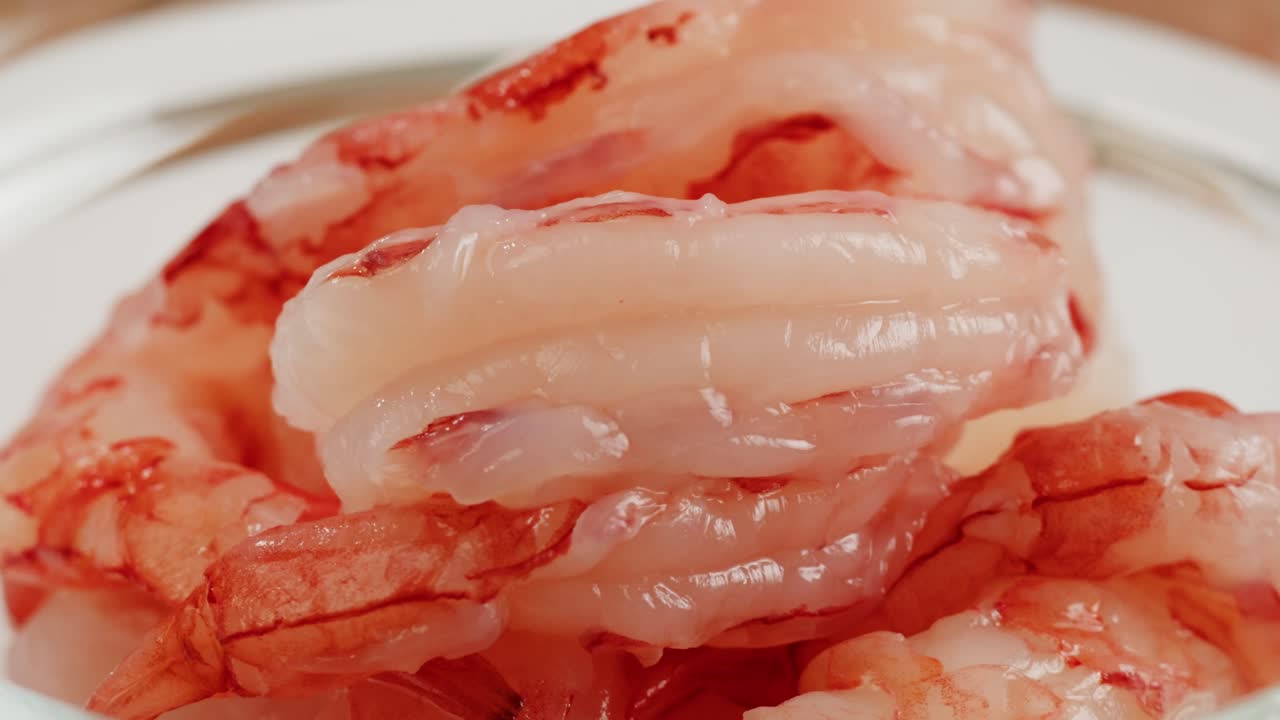 Gamberi per sashimi e gamberi sgusciati, disposti su un tagliere di legno, sono pronti per la cottura.