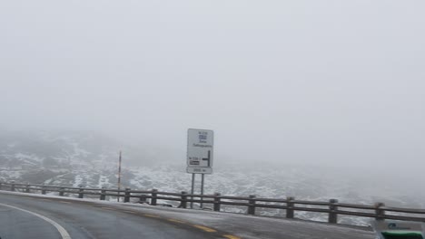 driving on a  wet snowy mountain road taking a sharp turn on a foggy day with low visibility