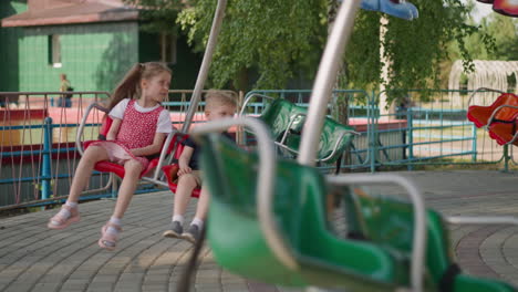 los niños pequeños montan una atracción de marry-go-round en el parque de la ciudad