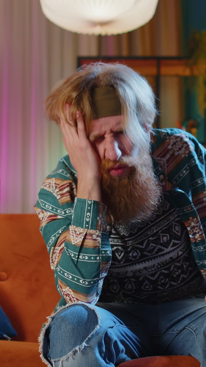 Uomo hippie scontento che si sfregia le tempie per curare il problema del mal di testa che soffre di stress da emicrania