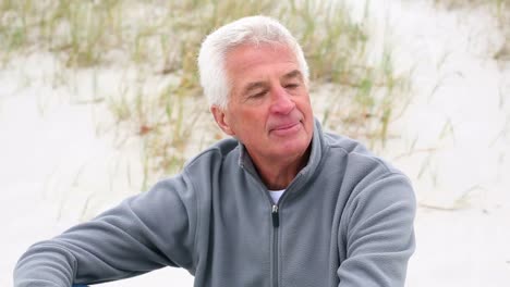 Retired-white-haired-man-relaxing-on-the-beach