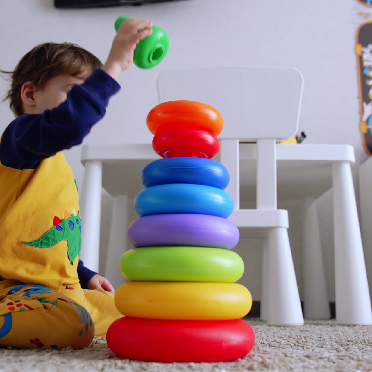 Niño pequeño adorable de dos años construyendo una pirámide en casa. El niño está sentado en el suelo, absorto en su juego. Vista de ángulo bajo.