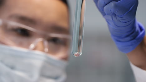 female scientist looking at test tube with lab-grown meat