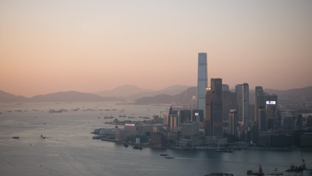 Vista aerea in hyperlapse dello skyline di Hong Kong al tramonto, con Victoria Harbour, fitti grattacieli e un cielo caldo e velato, iconico paesaggio urbano asiatico