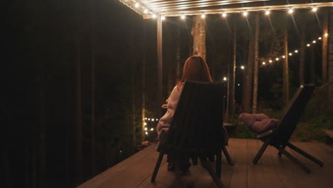 woman wrapping in plaid luxuriates in serenity of outdoors in armchair. lonely lady invests moments contemplating and envisioning aspirations for future