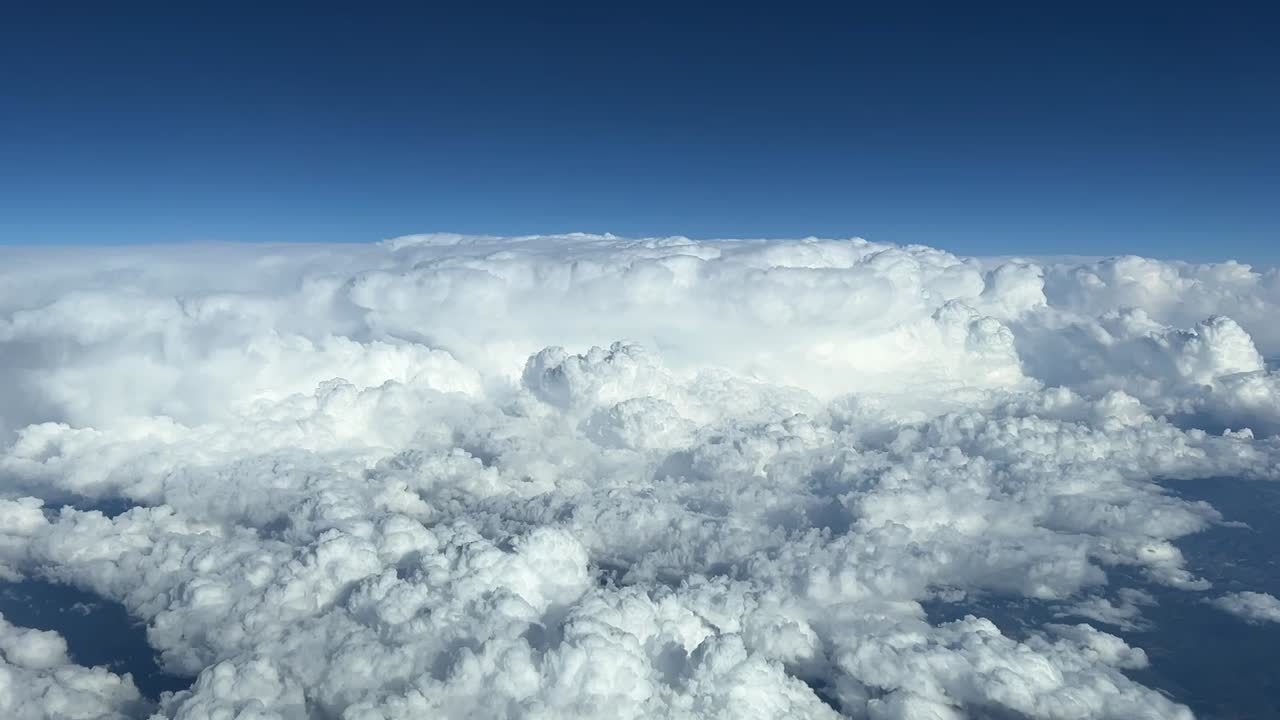 Aerial cockpit view of some  huge cumulonimbus taken at cruise level with a deep blue sky, daylight
