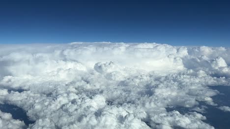 aerial cockpit view of some  huge cumulonimbus taken at cruise level with a deep blue sky, daylight