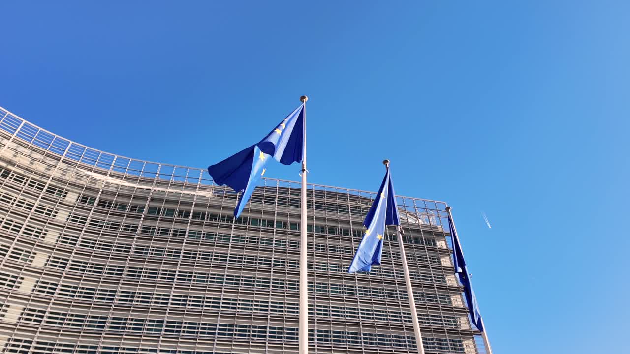 European Commission headquarters with EU flags under blue sky