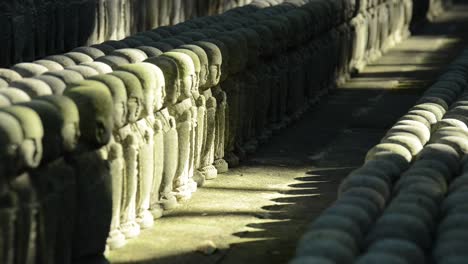 Konzentrieren-Sie-Sich-Langsam-Auf-Endlose-Reihen-Von-Jizo-Steinstatuen,-Die-Von-Sanftem-Morgenlicht-Und-Schatten-Beleuchtet-Werden