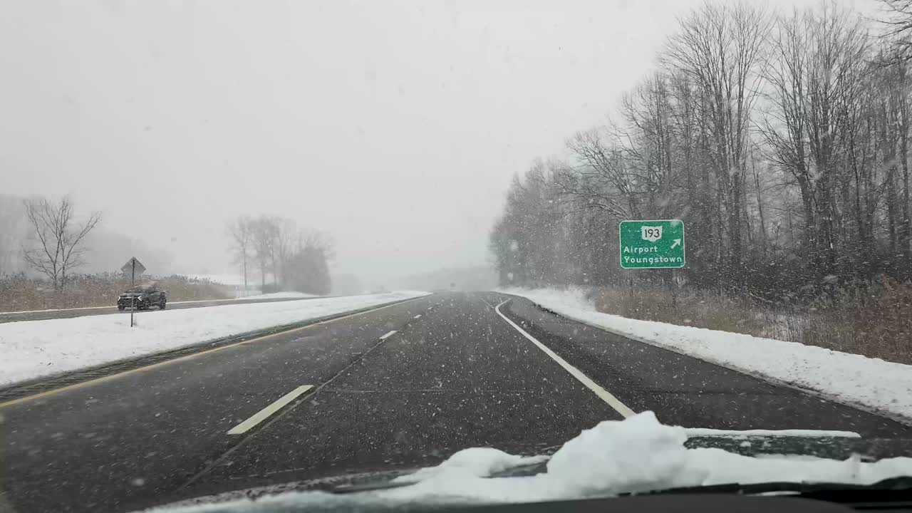 A footage of vehicle driving on a snow-covered highway during a winter snowfall, capturing the cold and serene landscape. Ideal for winter travel and weather-related projects.