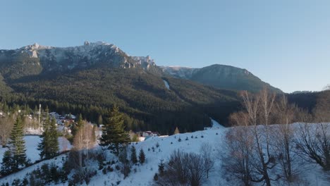 Snowy mountain village at the base of a forested peak during a clear winter day