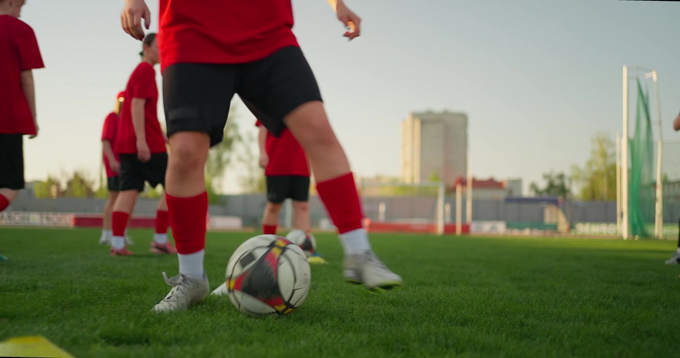 Jóvenes futbolistas practicando regates en un campo verde