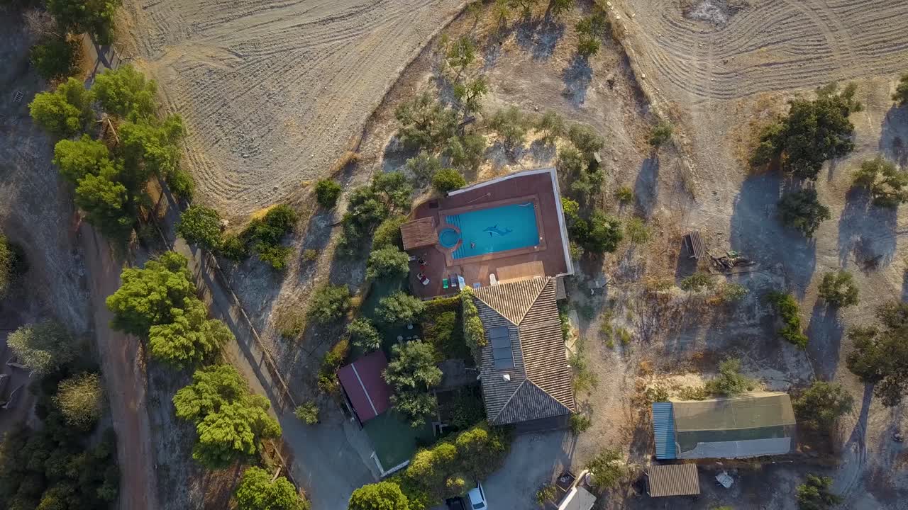 disparo aéreo descendente sobre una gran casa de campo española con campos de olivos en andalucía