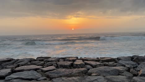 Herrlicher-Blick-Auf-Die-Meereslandschaft-Bei-Sonnenuntergang-Mit-Wellen,-Die-Sich-An-Den-Wellenbrechern-Brechen