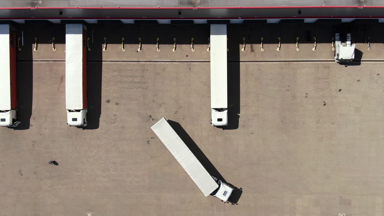 화물 트레일러가 있는 세미 트럭이 물류 공원의 창고 주차장을 따라 이동하고 있습니다.