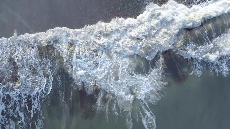 Cenital shot of the crushing waves by the beach in the morning in Carilo, Argentina