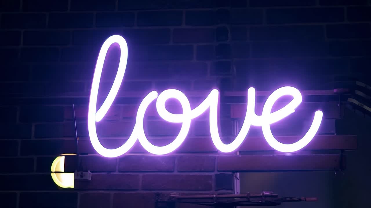 el letrero de neón púrpura que brilla con la palabra amor contra una pared de ladrillo de textura crea una atmósfera romántica y vibrante