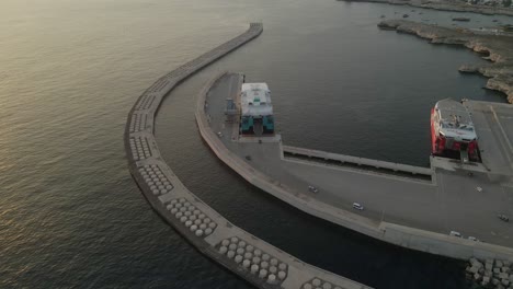 drone flying above shipping docks at sunset with boats loading up ready to depart