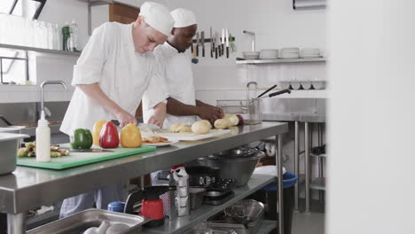 dos cocineros varones diversos cortando verduras en la cocina, en cámara lenta