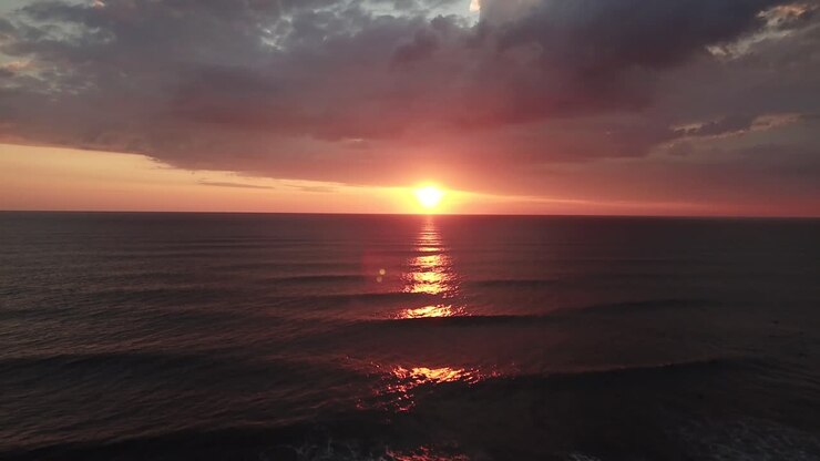 Slow relaxing drone footage flying toward the ocean with the sun about to set in the background, Costa Rica