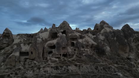 historical stone caves against cloudy sky in cappadocia, turkey