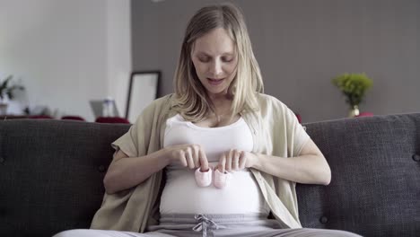 front view of pregnant woman playing with babys bootees on belly