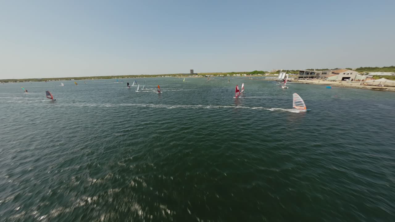 disparo de drone de bajo a alto que muestra un centro de deportes acuáticos y windsurfistas durante un soleado día de verano