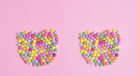 colorful chocolate candies making eg shape on bright pink background. stop motion flat lay