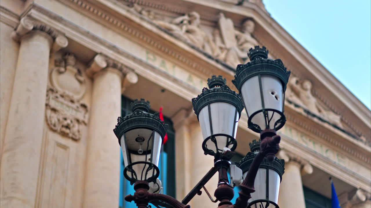Close up of a street lamp with a blurred view of the Nice courthouse on the background