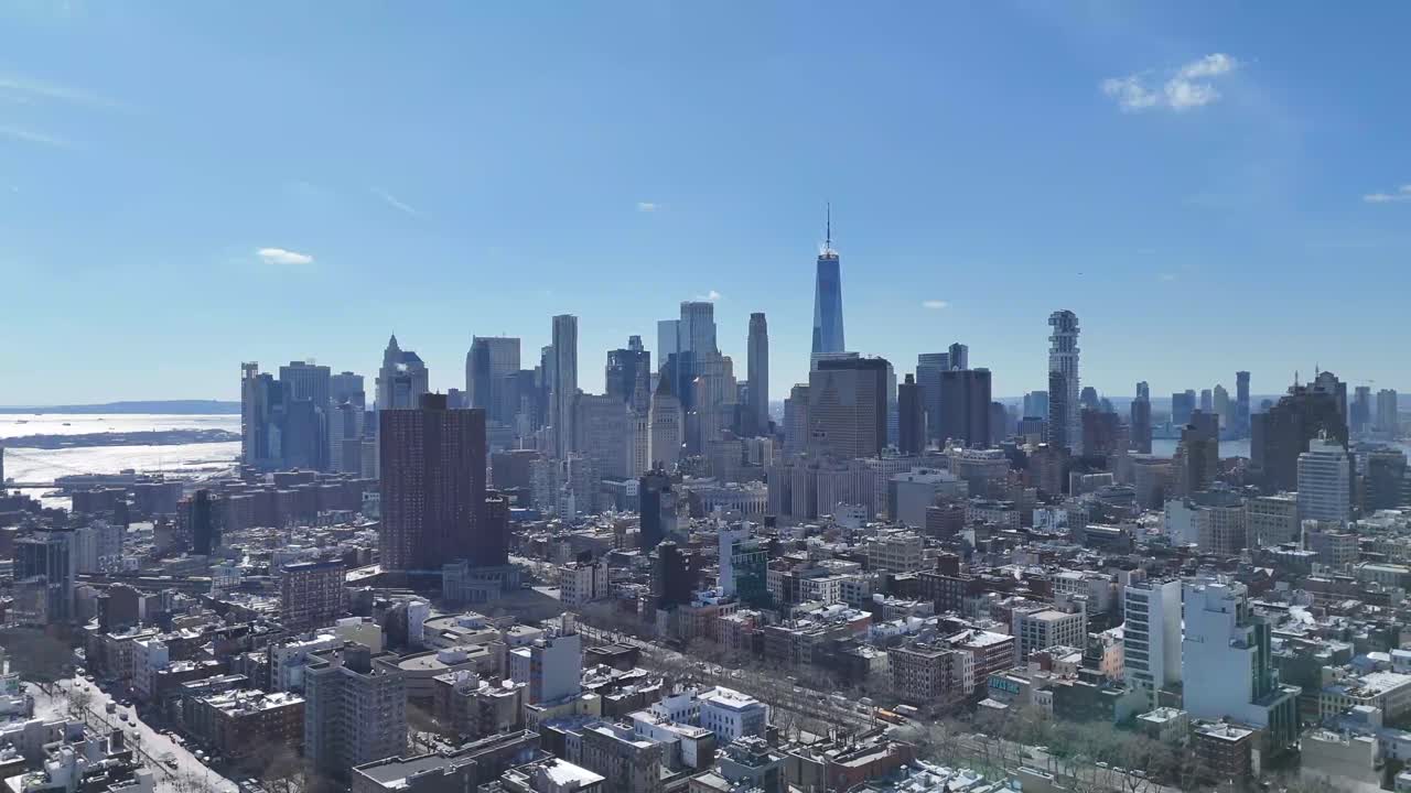 Horizontal drone side-tracking shot over Broome Avenue in New York, showcasing the city's vibrant streets and historic buildings with the stunning New York skyline in the background.