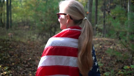 primer plano de una mujer mirando a la izquierda y caminando por un bosque con una bandera envuelta alrededor de ella