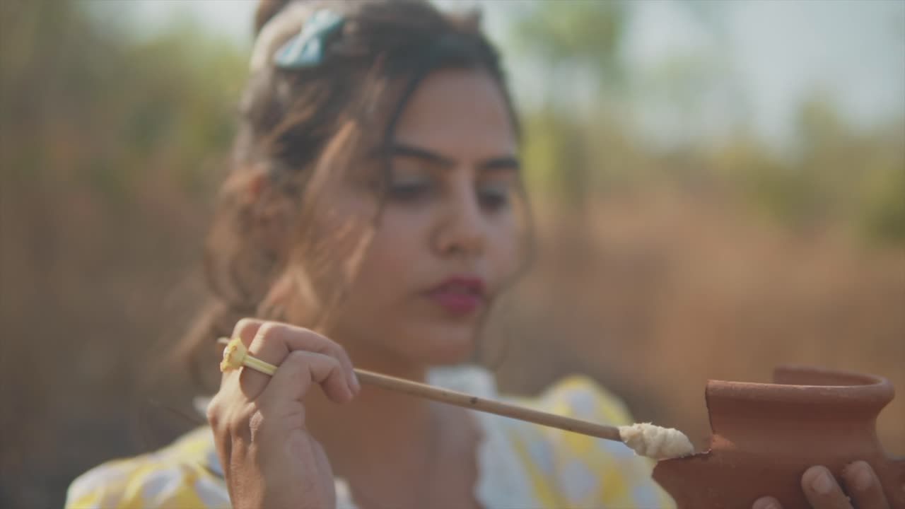 Female holding a small pot in one hand and glue in the other focused carefully applying glue to the edge of the pot she is holding