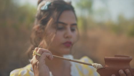 female holding a small pot in one hand and glue in the other focused carefully applying glue to the edge of the pot she is holding